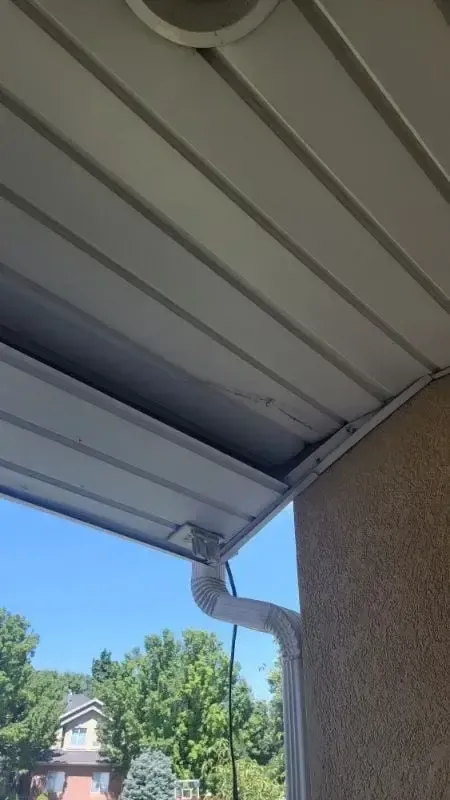 Exterior soffit and fascia beside a downspout along a stucco eave