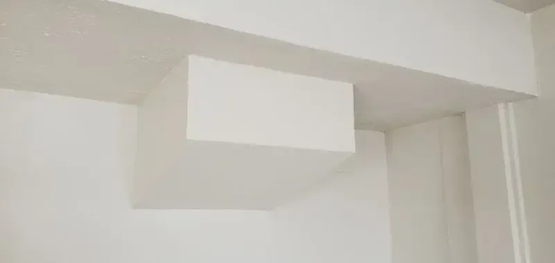 Finished drywall soffit and boxed beam at a ceiling corner, taped and painted white