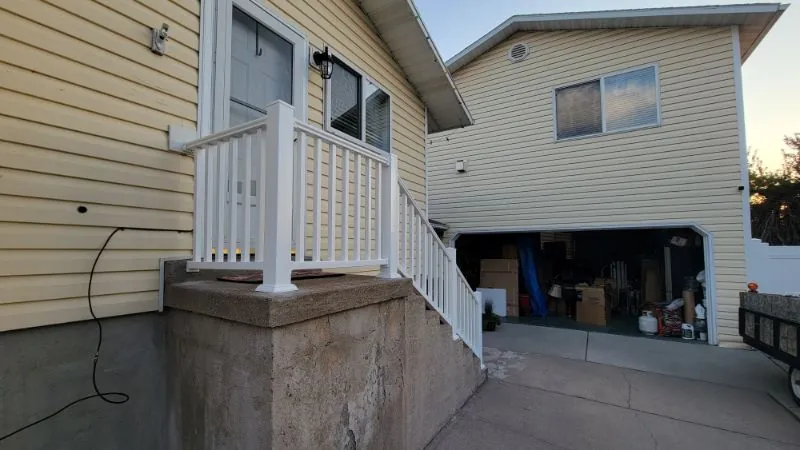 Concrete steps and a white railing beside an open garage