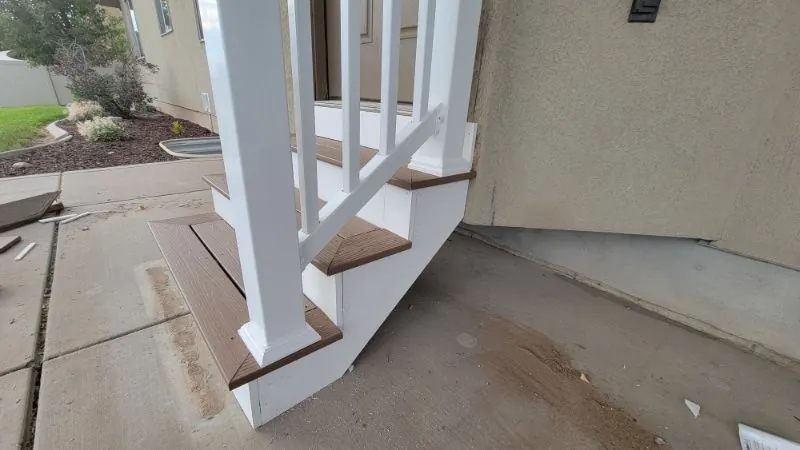 Entry steps with white railing posts against a stucco wall