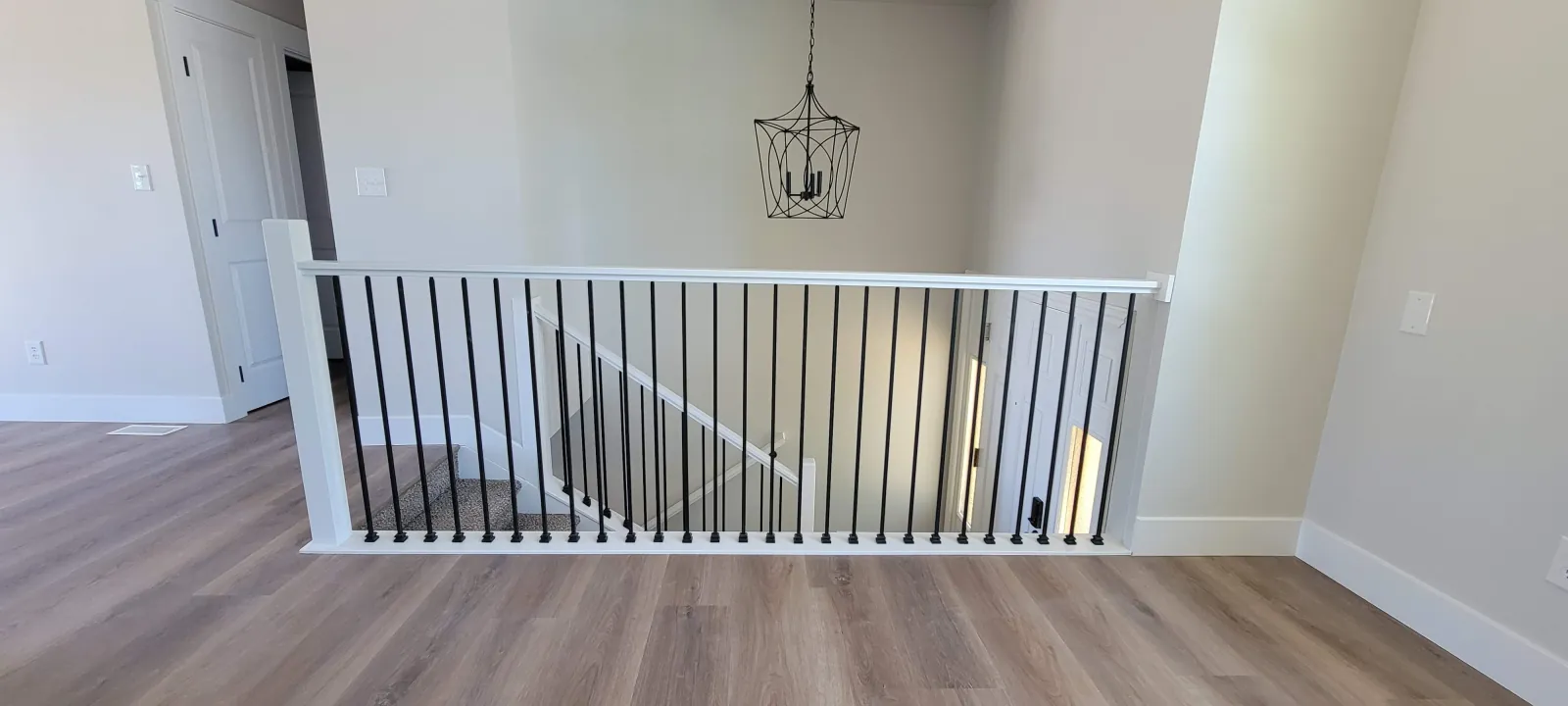 Upstairs landing with a new black and white stair railing under a pendant light