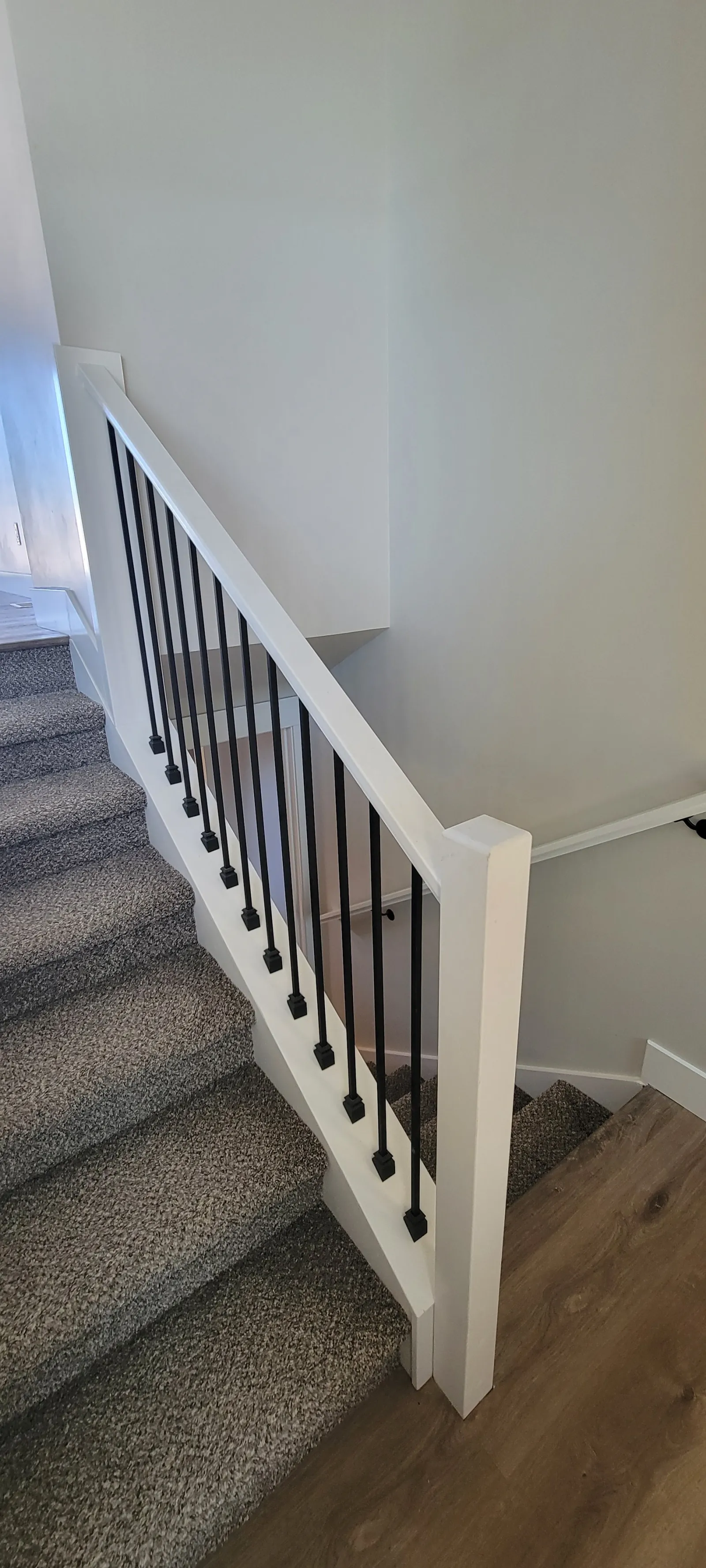 Staircase with white balusters and carpeted treads