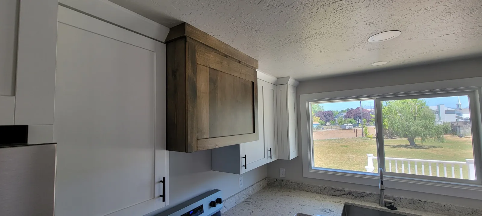 Kitchen cabinets and countertop beside a large picture window