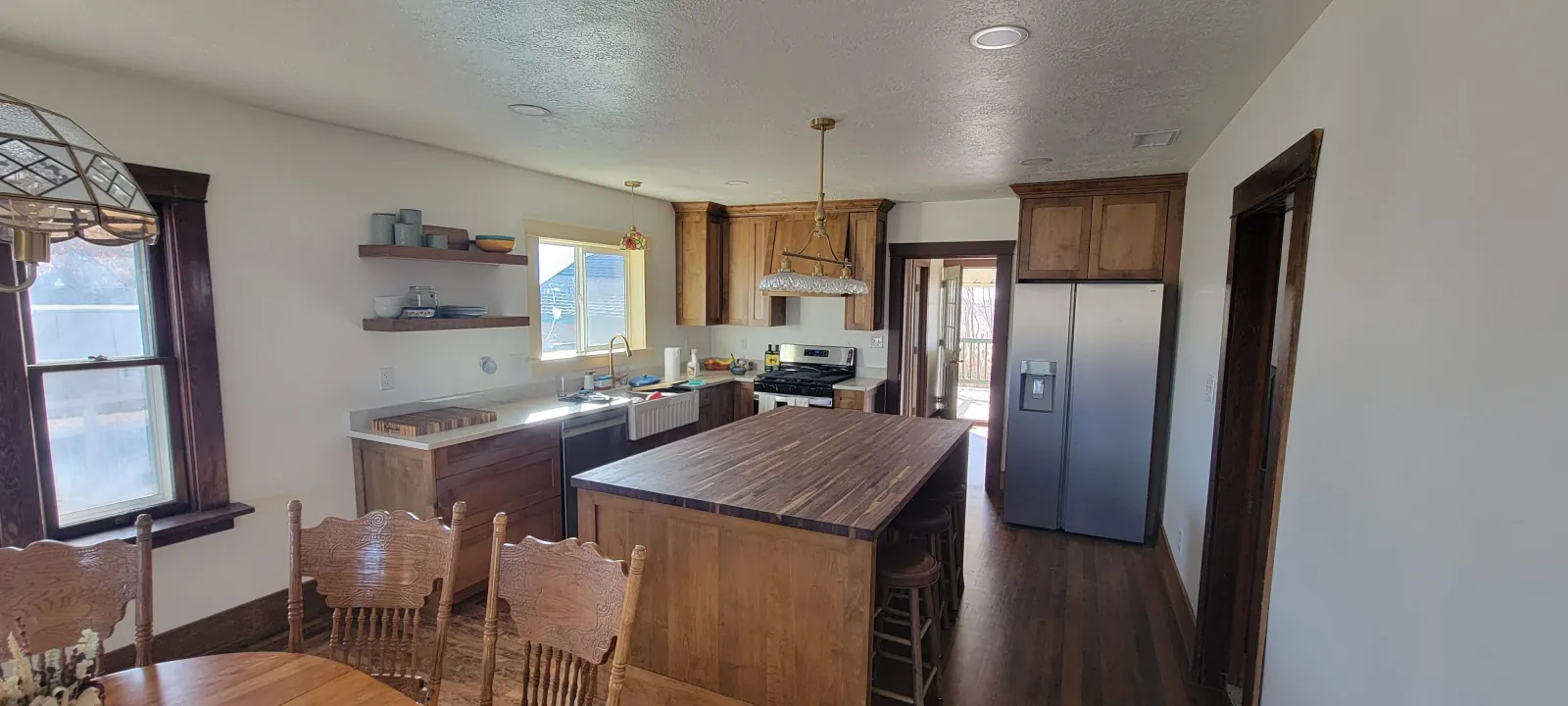 Kitchen with knotty alder cabinets, a butcher block island and floating shelves