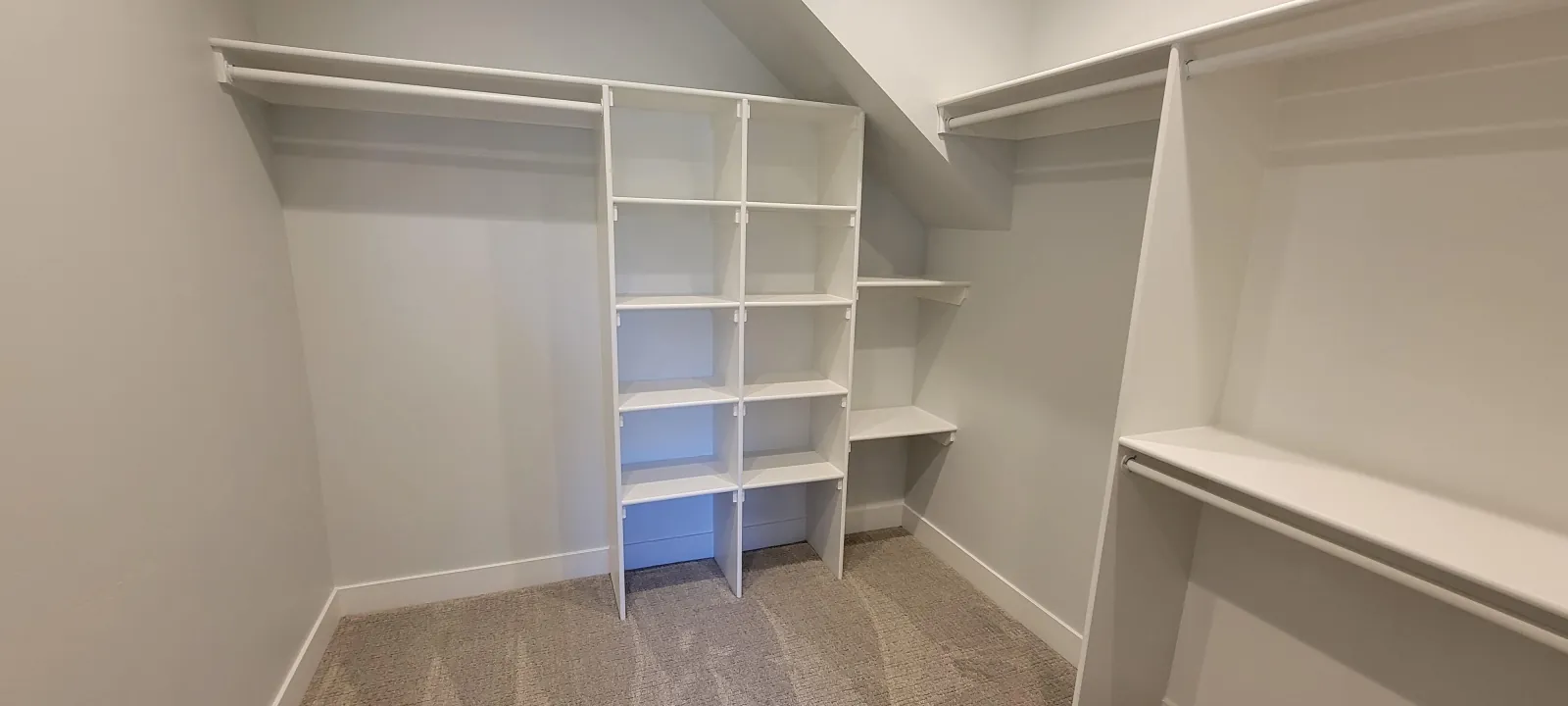 Built-in closet shelving and hanging rails fitted under a sloped ceiling