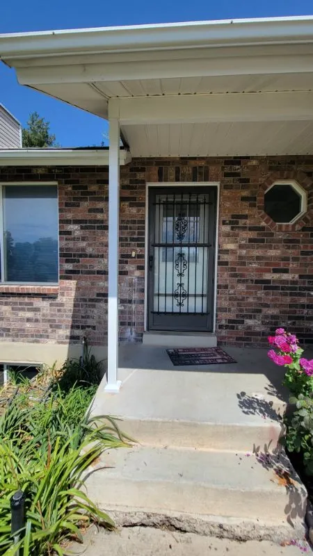 Brick home entry with a security door and a concrete walkway
