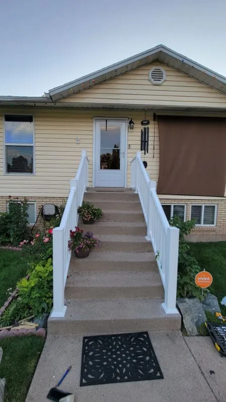 Front entrance with concrete steps and a white handrail