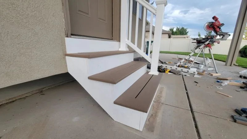 Front entry steps with a new white railing, saw set up on the driveway