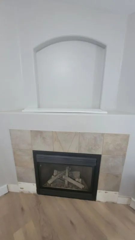 Corner fireplace with a tile surround and arched niche before refacing