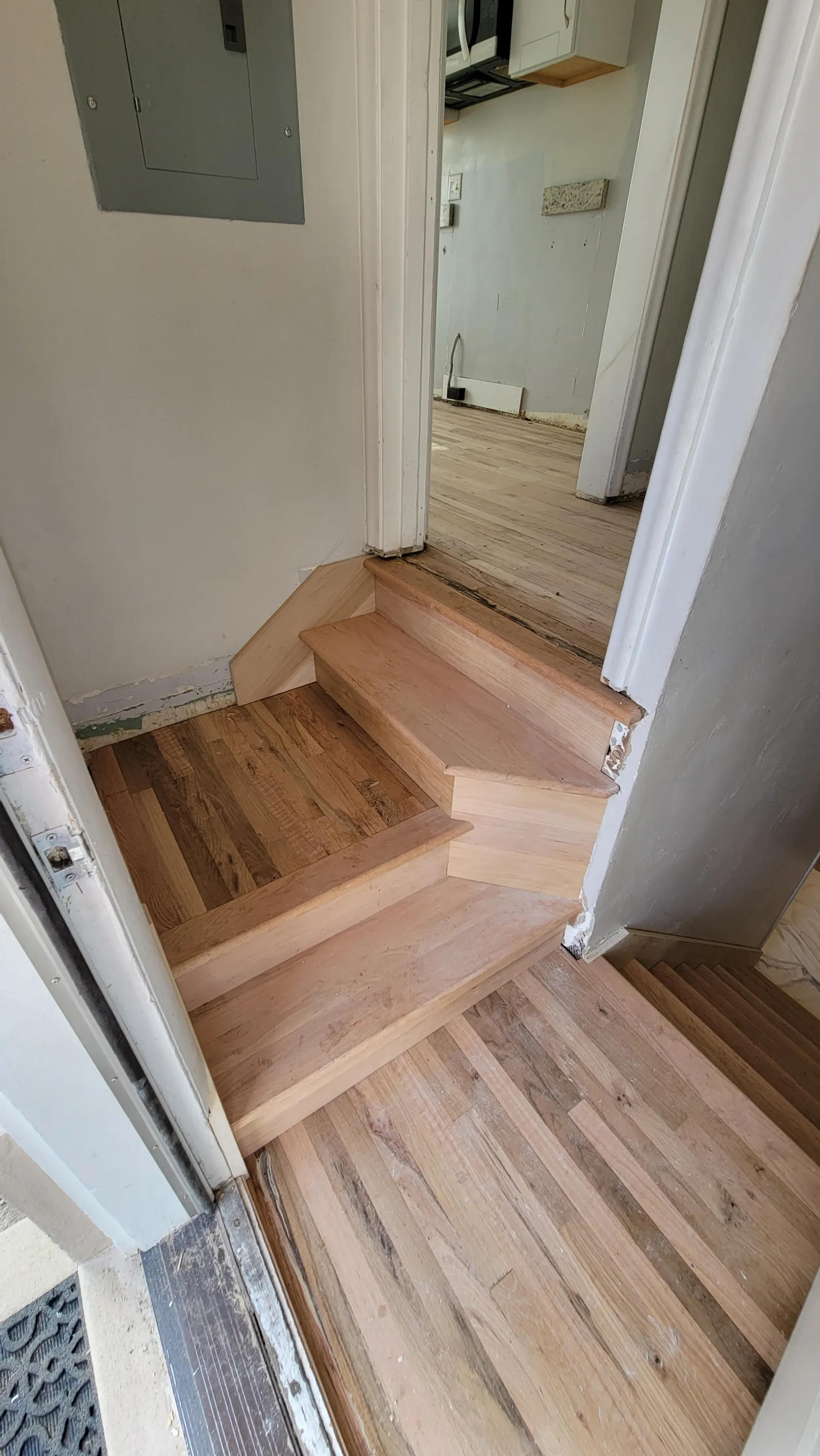 New oak stair treads and risers fitted into an existing hardwood floor at a landing