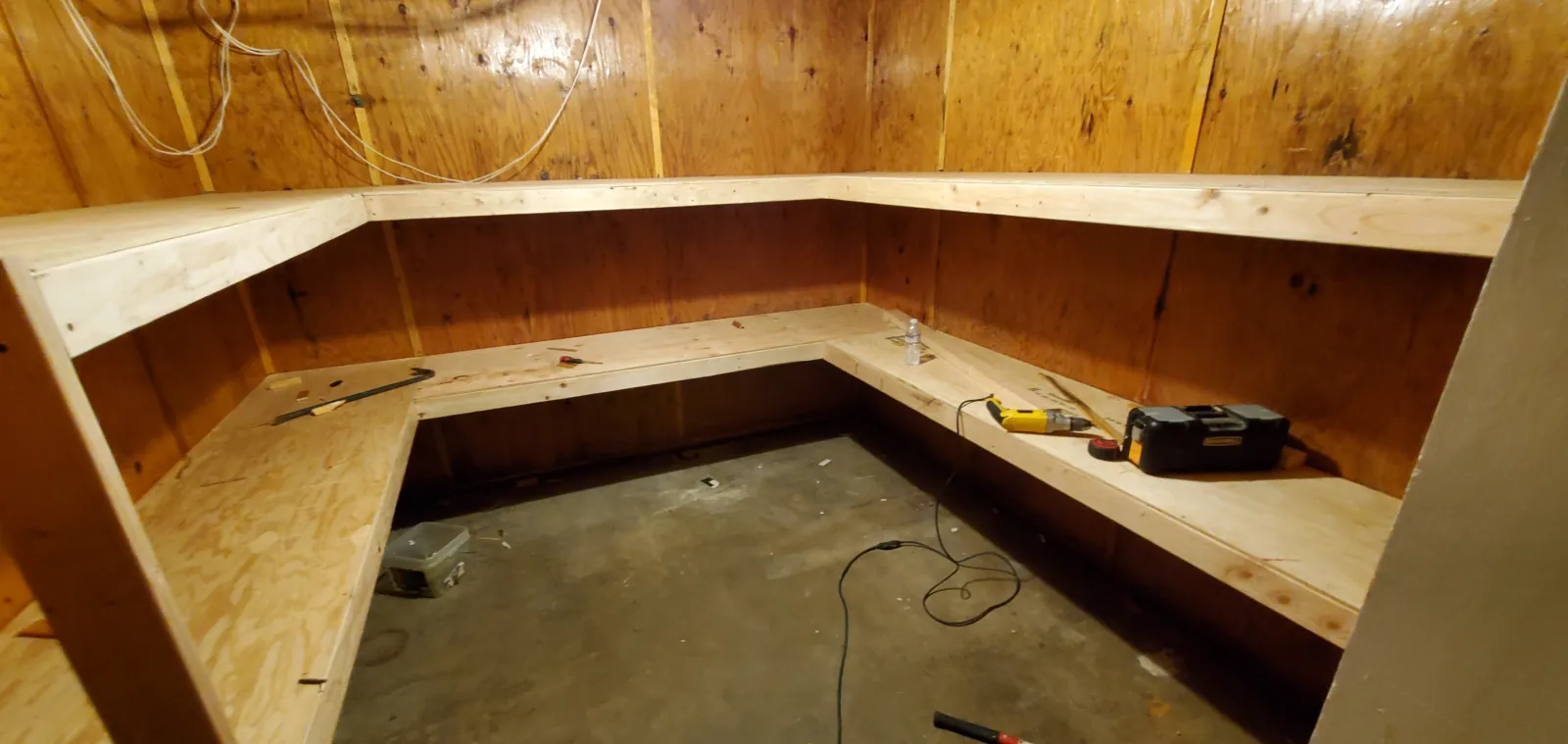 Wood-framed corner banquette bench under construction with a plywood top