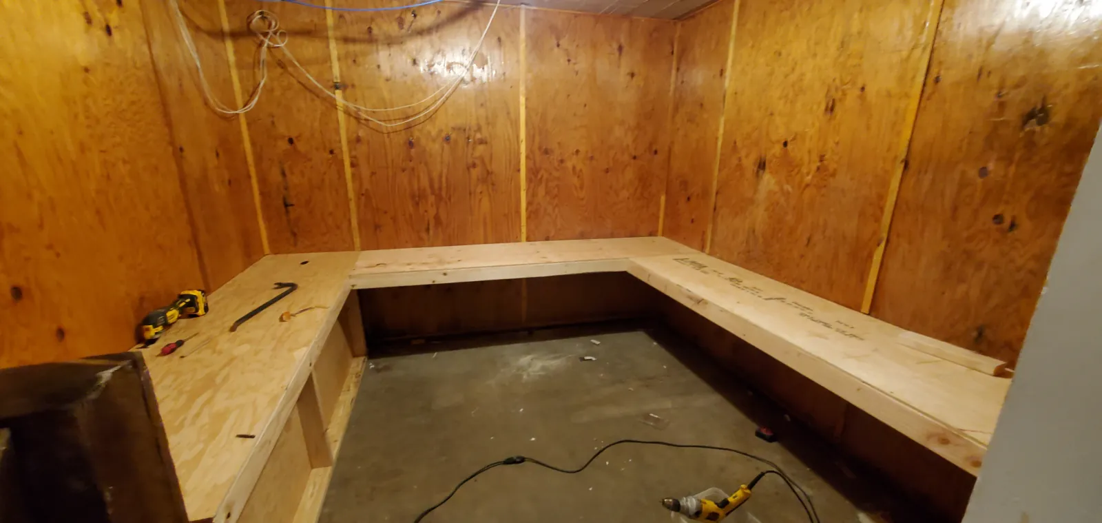 L-shaped built-in bench framed from dimensional lumber and plywood against panelled walls