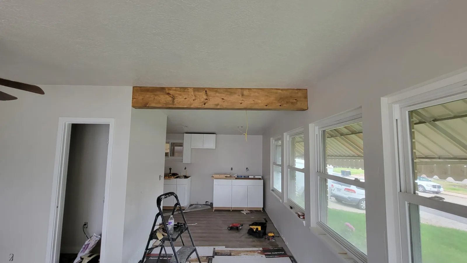Open-plan room during work with a stained wood beam across the ceiling