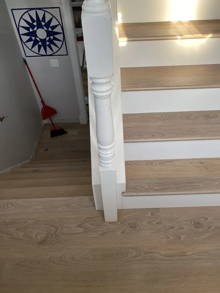 New wood-look stair treads with white risers beside a white newel post