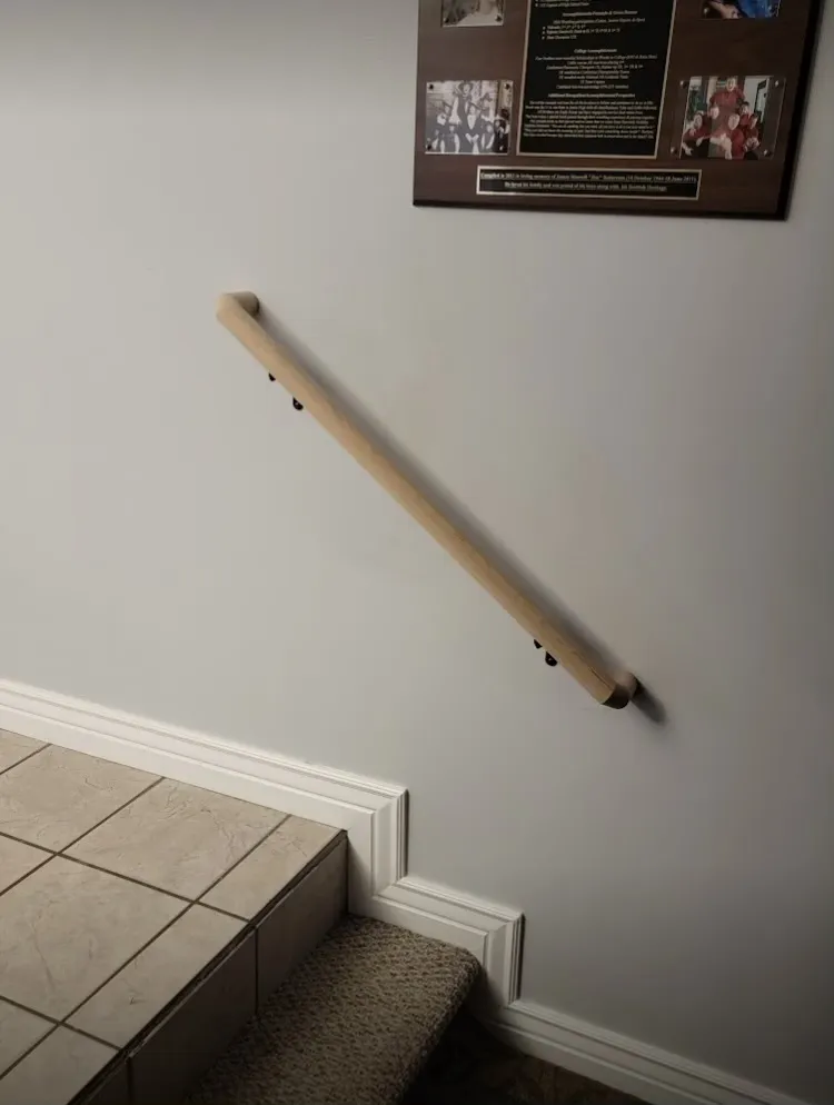 Wood handrail mounted on a wall above tiled steps