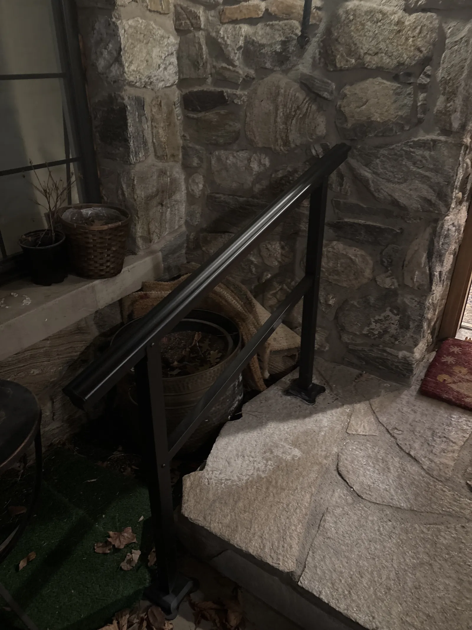 Black metal handrail beside a stone step