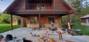 Miter saw and trim stock set up on a patio during exterior carpentry work on a timber home