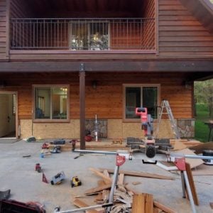 Miter saw and trim stock set up on a patio during exterior carpentry work on a timber home